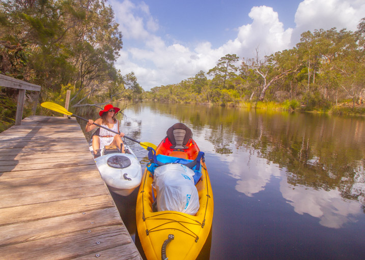 Girl with red hat sitting on a kayak while kayak camping upper noosa river.