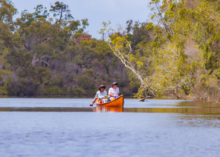 Two canoeists with grey hats making their way upriver while kayak camping in the upper noosa river